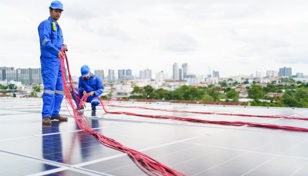 Engineers dressed in blue laying out cable conduit for a solar panel installation.