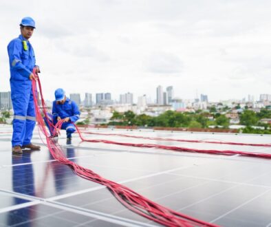 Engineers dressed in blue laying out cable conduit for a solar panel installation.